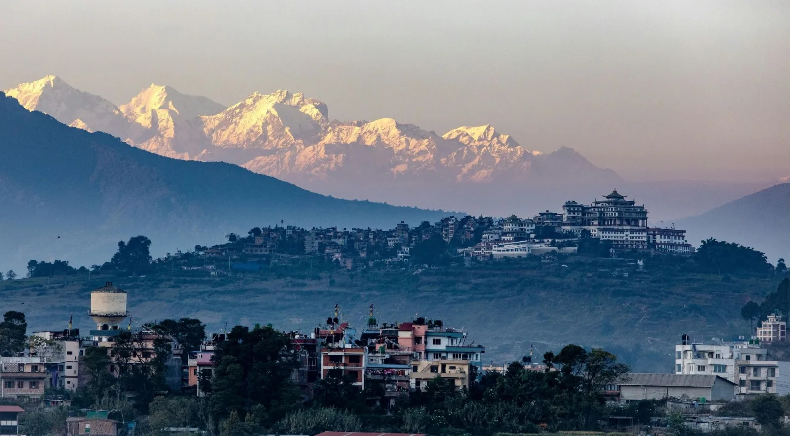 Kathmandu city skyline at dusk with the snow-capped Himalaya visible in the distance